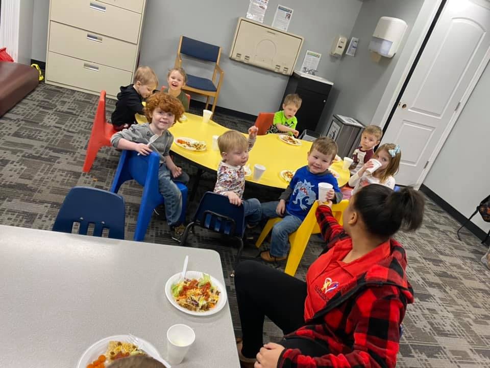 Adult and children sitting at tables with food and drinks
