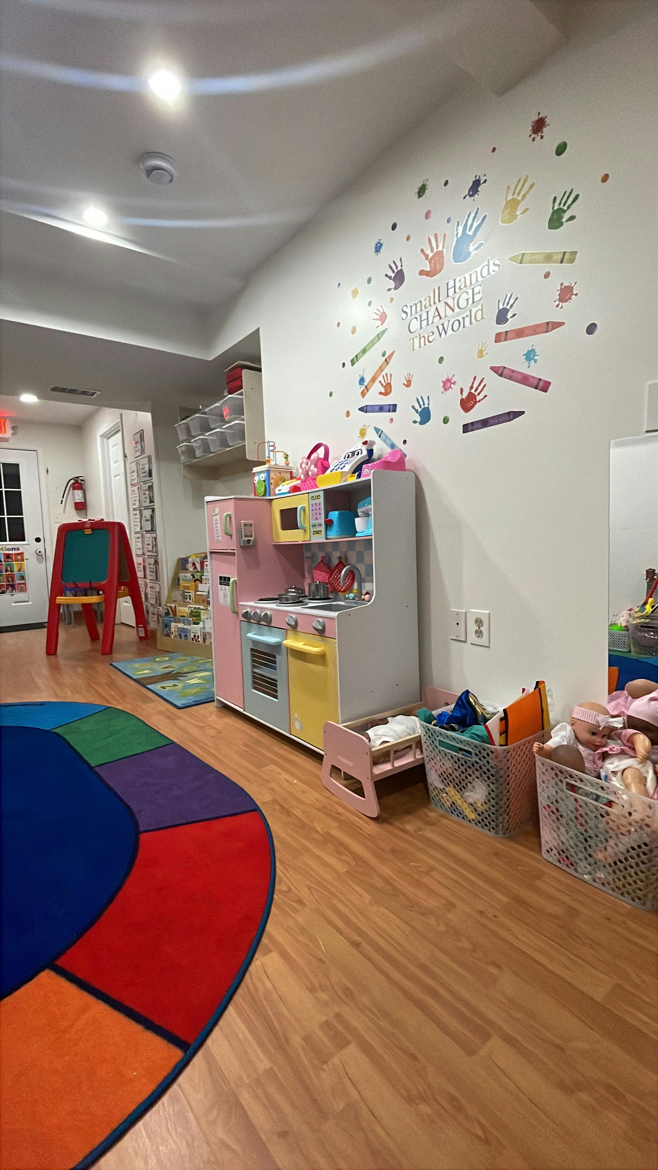 Playroom with toy kitchen, colorful rug, and wall decals