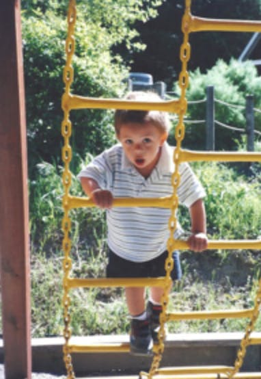 Child climbing a yellow rope ladder on a playground