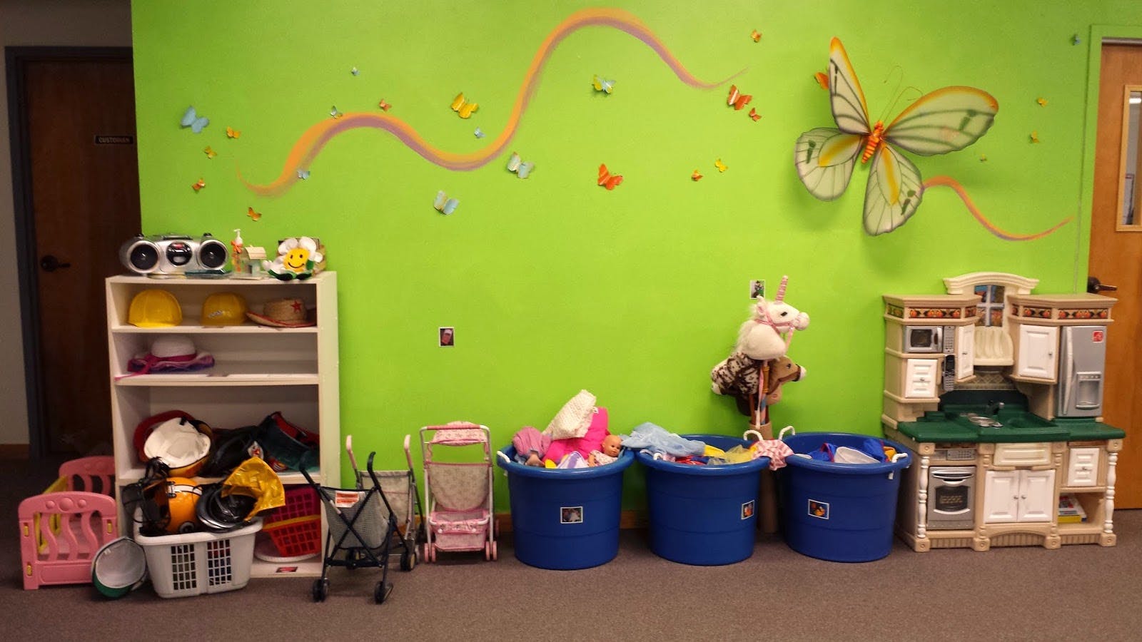 Playroom with toys, shelves, and a butterfly decoration on a green wall