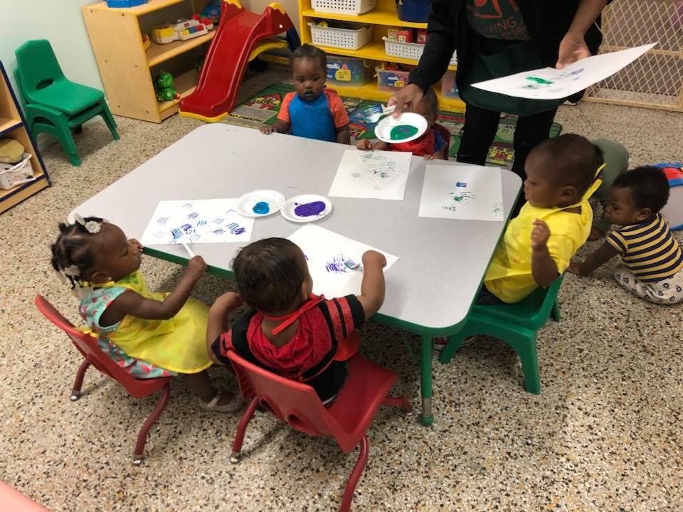 Children painting at a table in a classroom