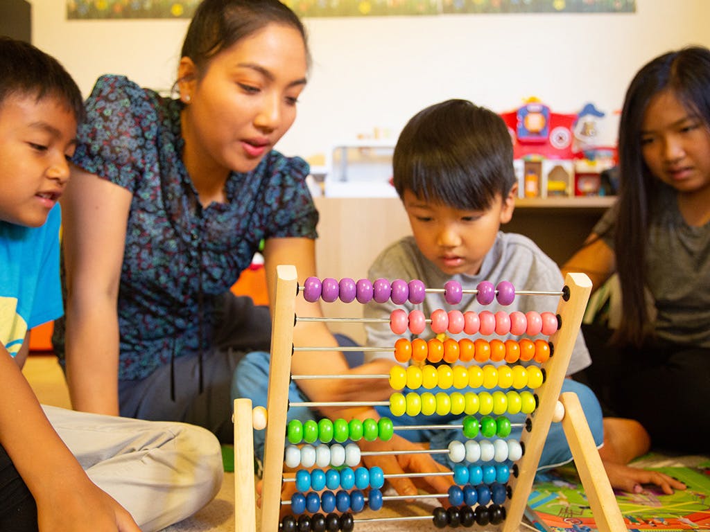 Adult and two children looking at an abacus