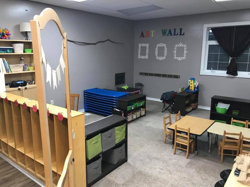 Classroom with small tables and chairs, storage units, and an art wall
