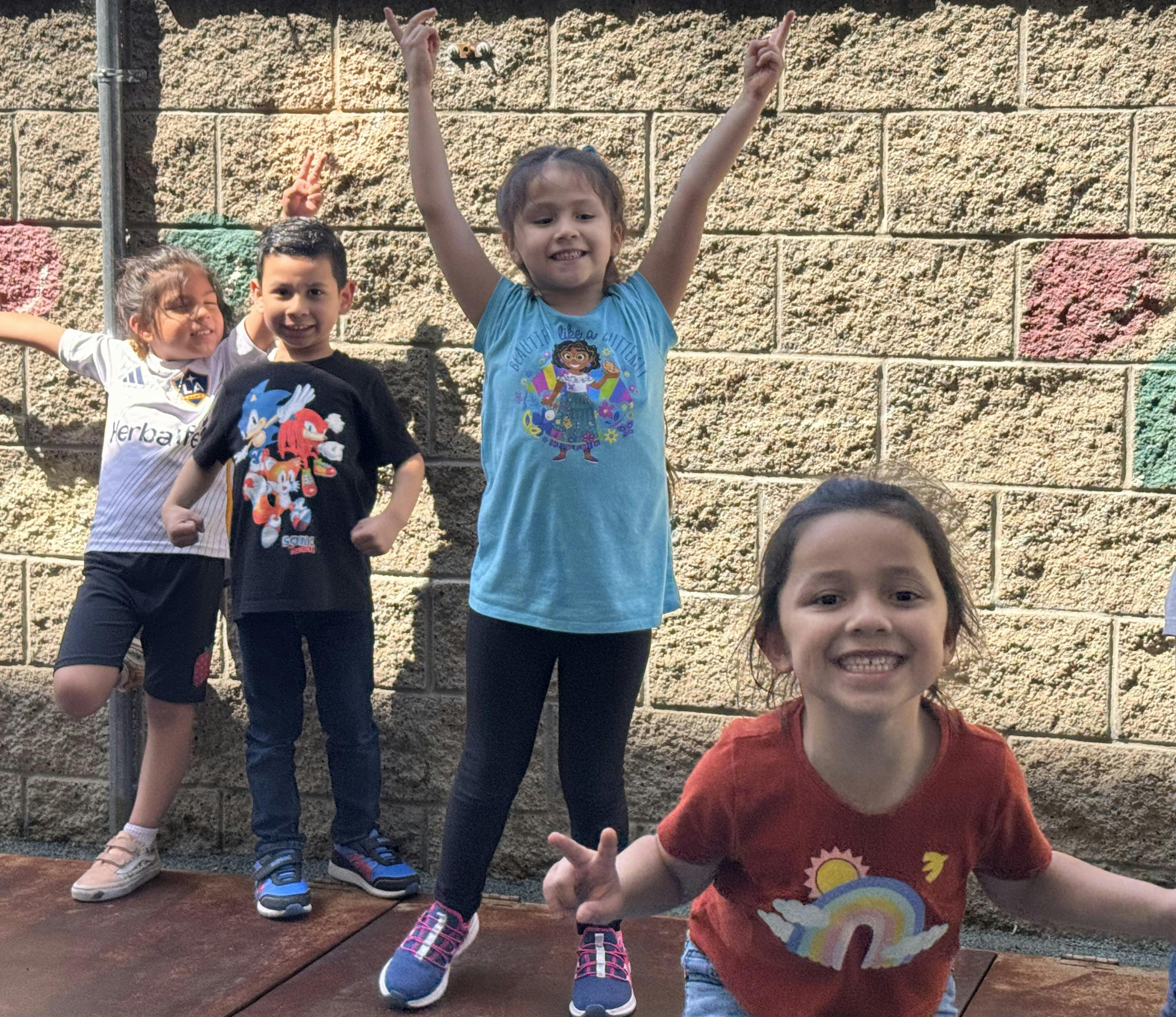 Four children posing for a photo, one with arms raised