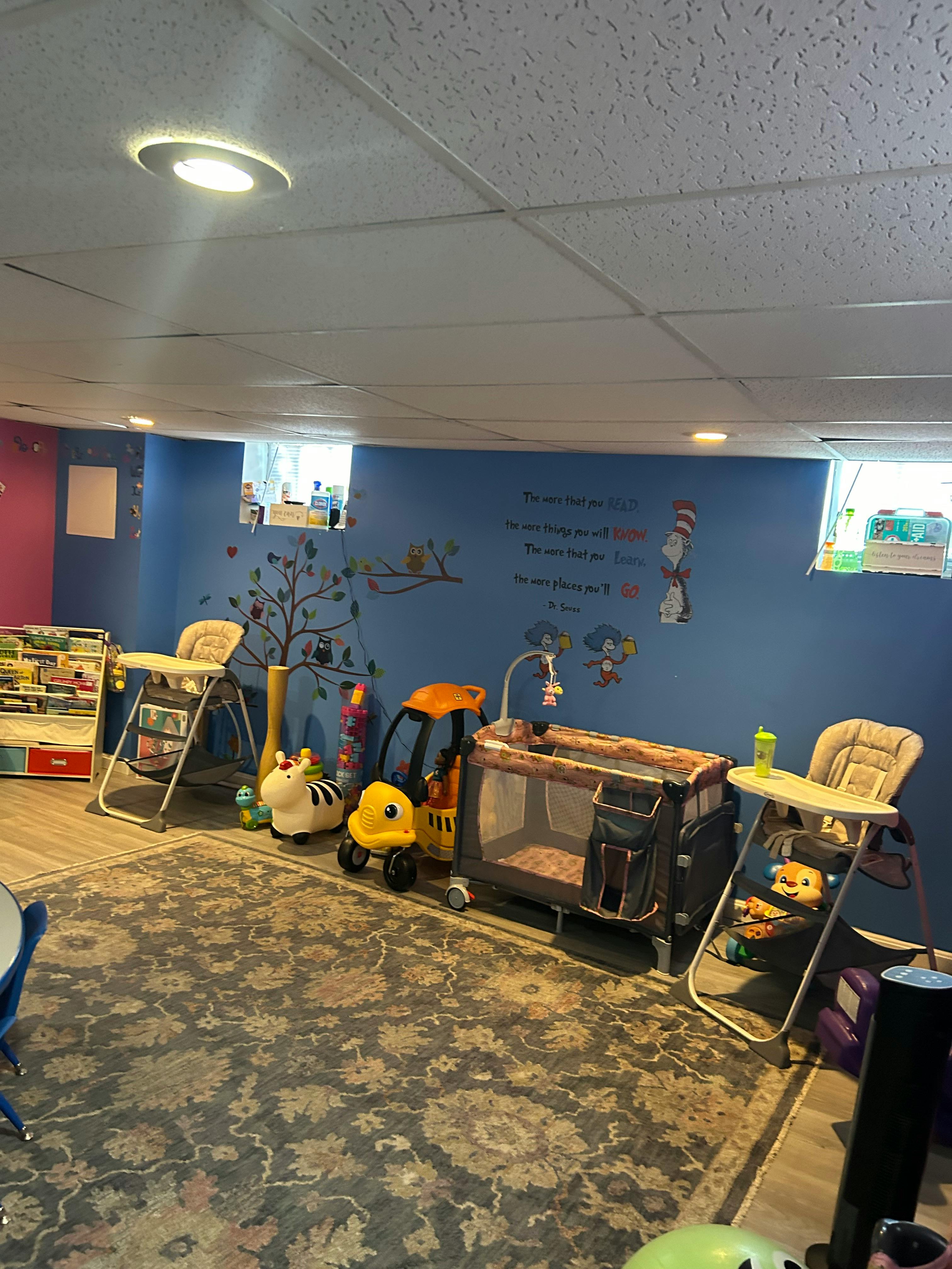 Nursery room with two high chairs, a playpen, and children's toys