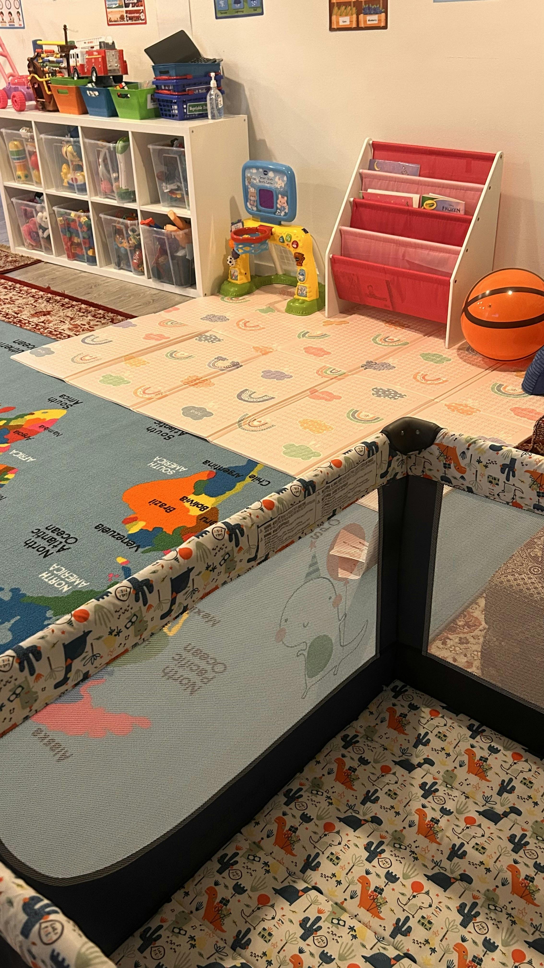 Playroom with a playpen, toy shelf, book rack, and play mats