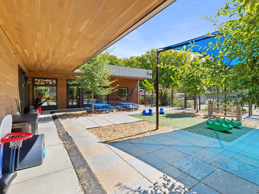 Outdoor playground area with blue picnic tables and rocking toys