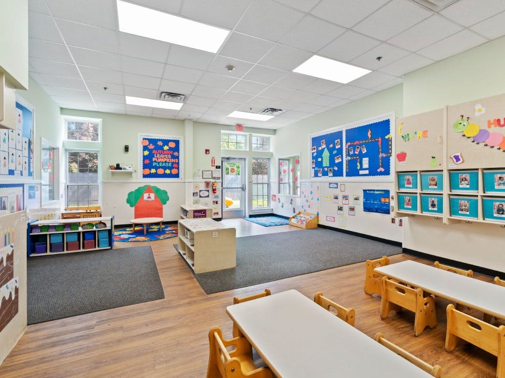 Classroom with small tables and chairs, play areas, and decorated walls