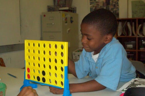 Child playing a board game with yellow and blue pieces