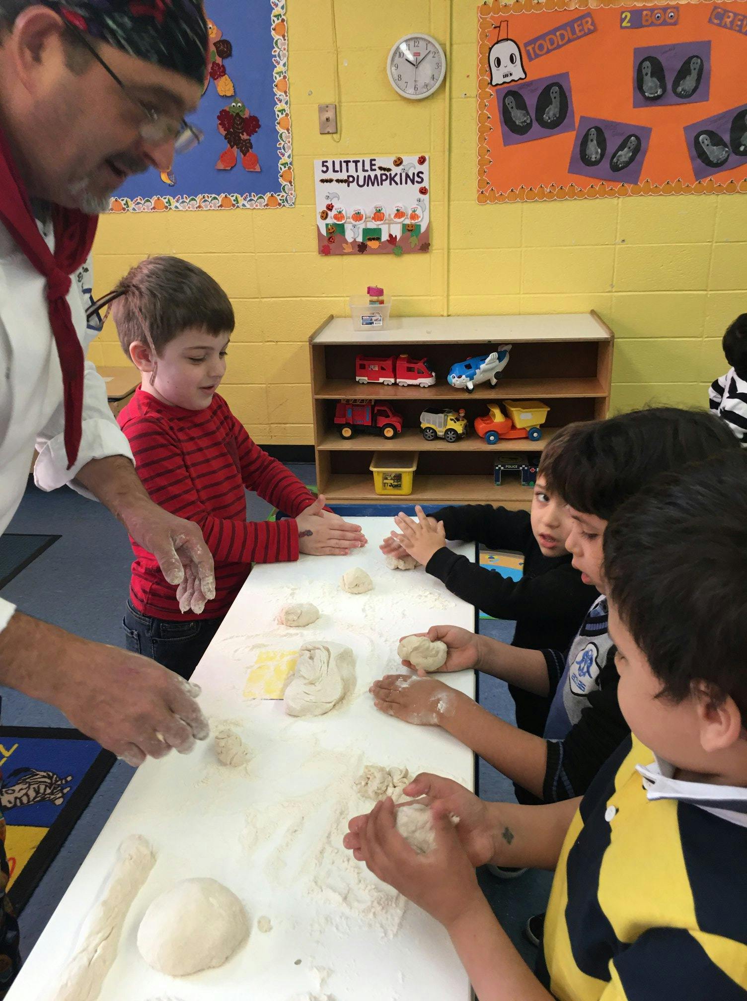 Adult and children making dough in a classroom