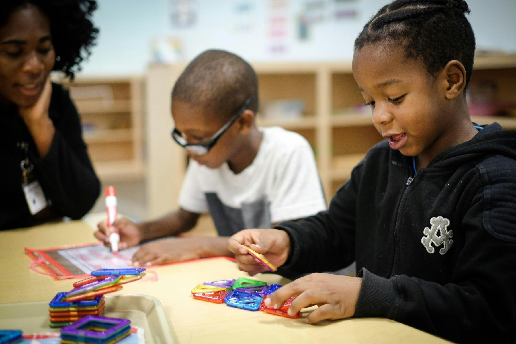 Adult and two children at a table with learning toys