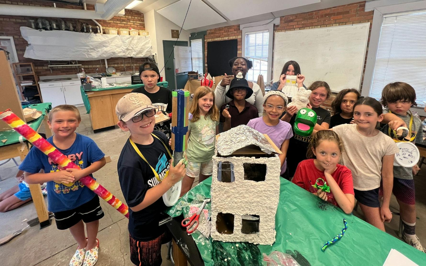 Group of children with crafts, including a house model