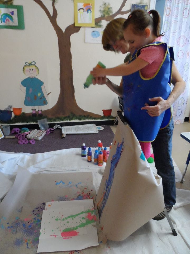 Adult and child painting together in a classroom
