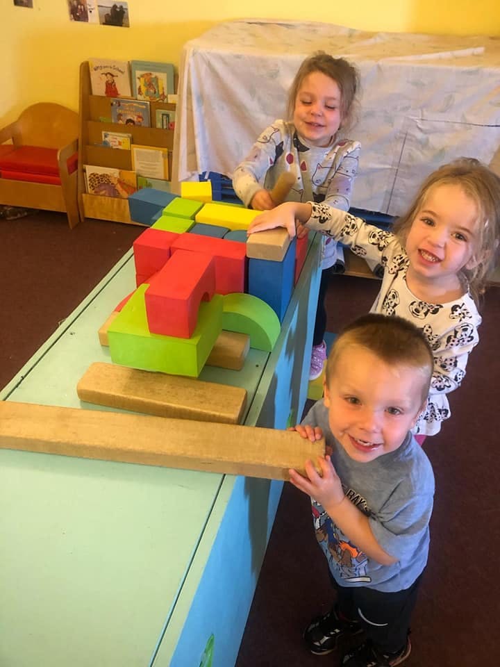 Three children playing with large colorful blocks