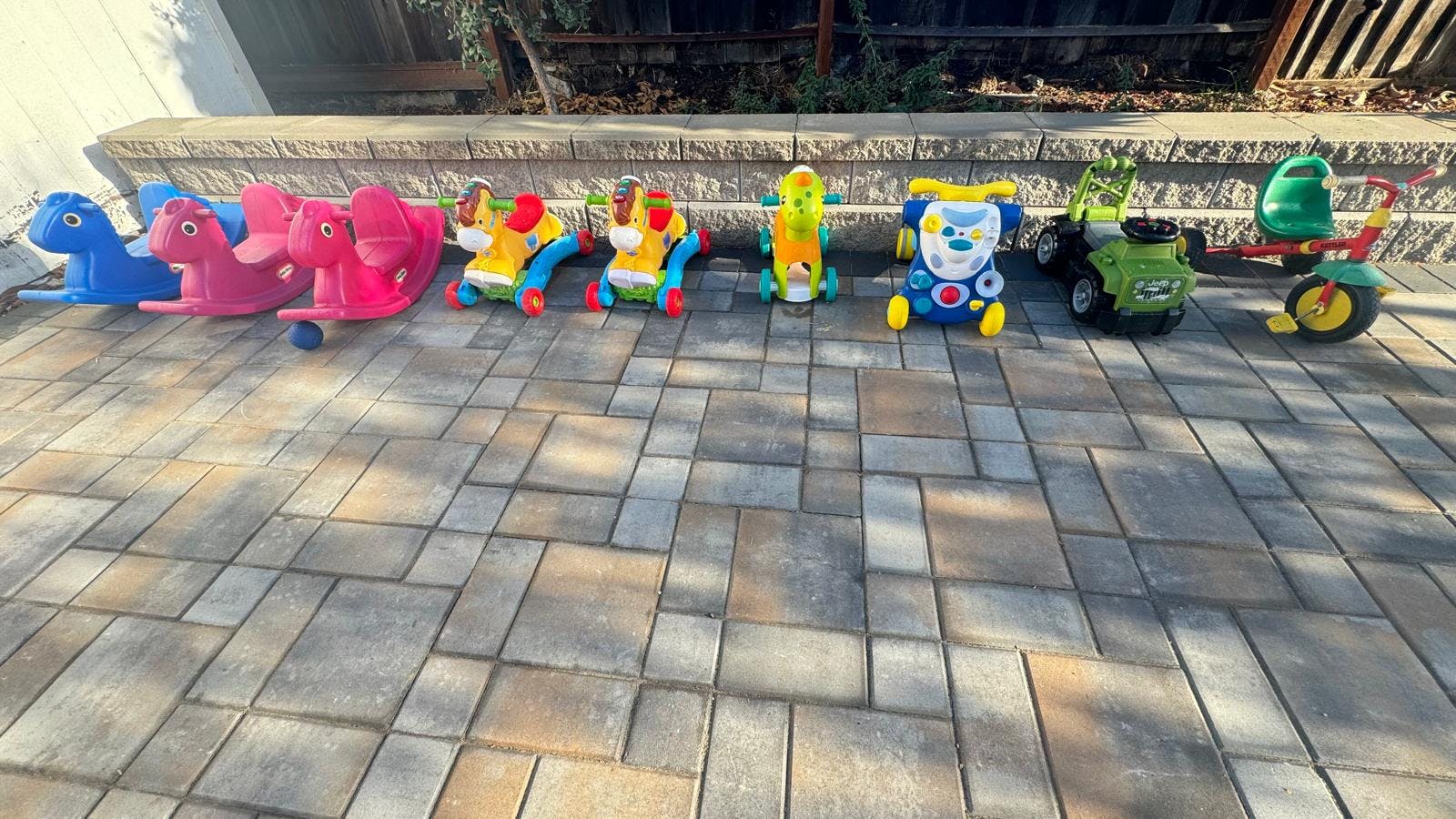 Multiple colorful ride-on toys lined up on a paved surface