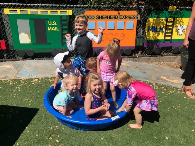 Children playing in a blue wading pool outdoors