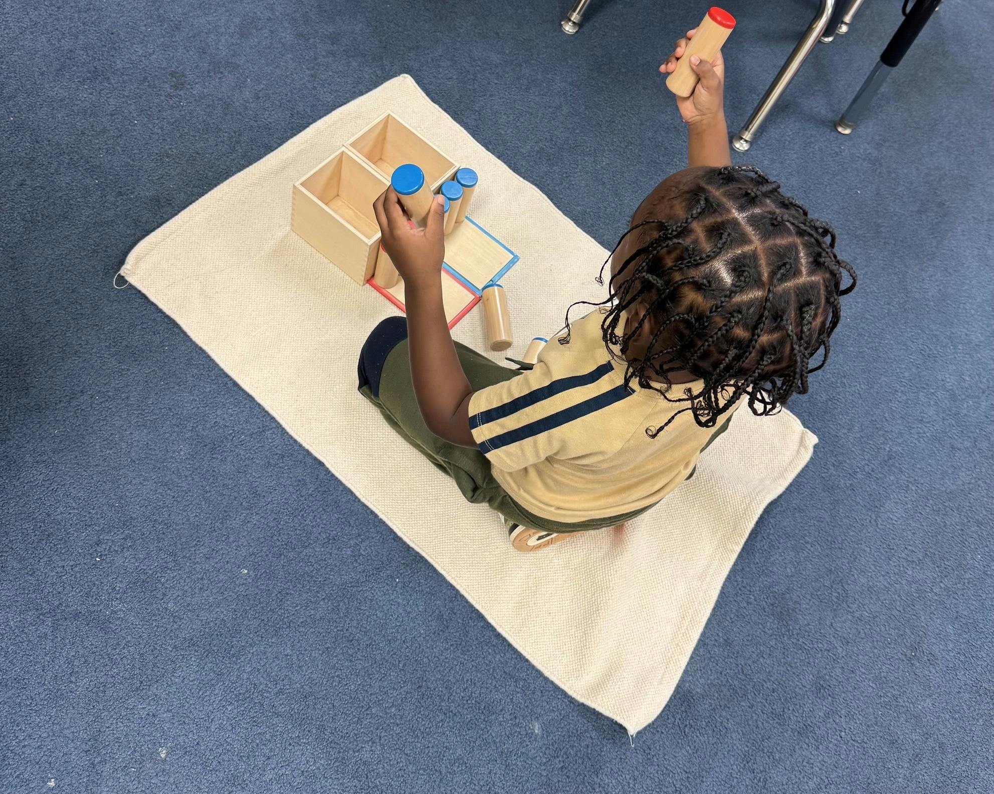 Child sitting on a mat playing with wooden blocks