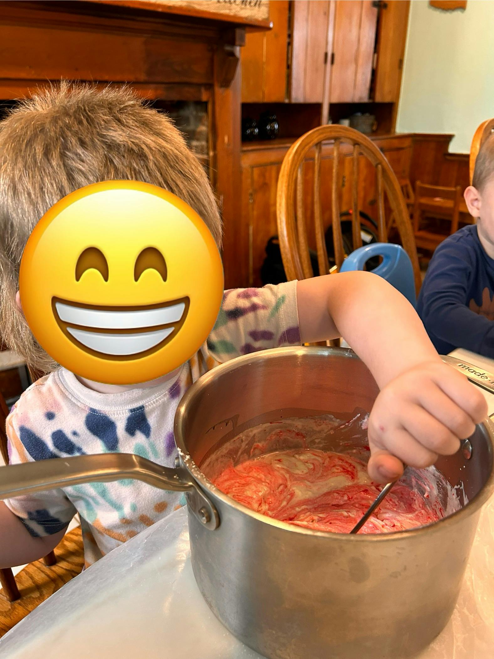Child stirring a pot of pink liquid