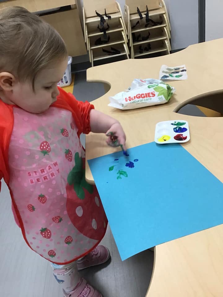 Child painting on blue paper at a table