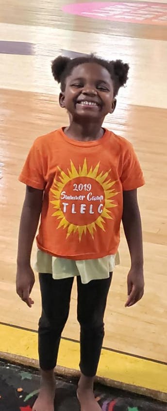 Child in orange t-shirt with "2019 Summer Camp TLELC" text