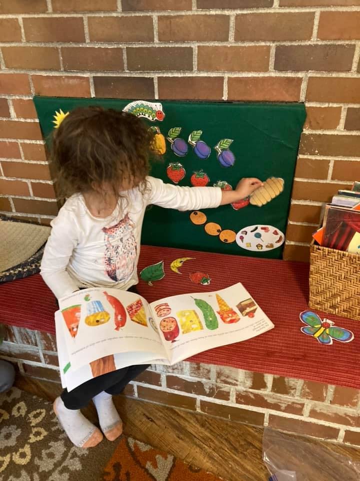 Child playing with a felt board and looking at a book