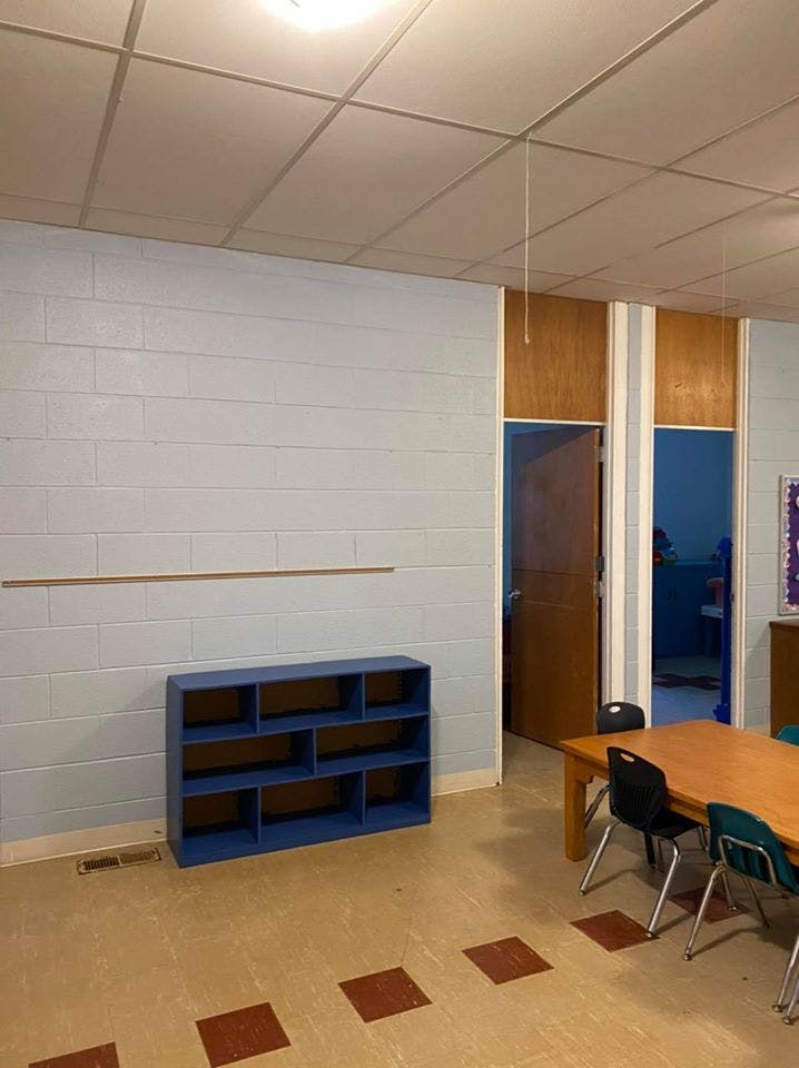 Empty classroom with blue shelving unit and wooden table with chairs