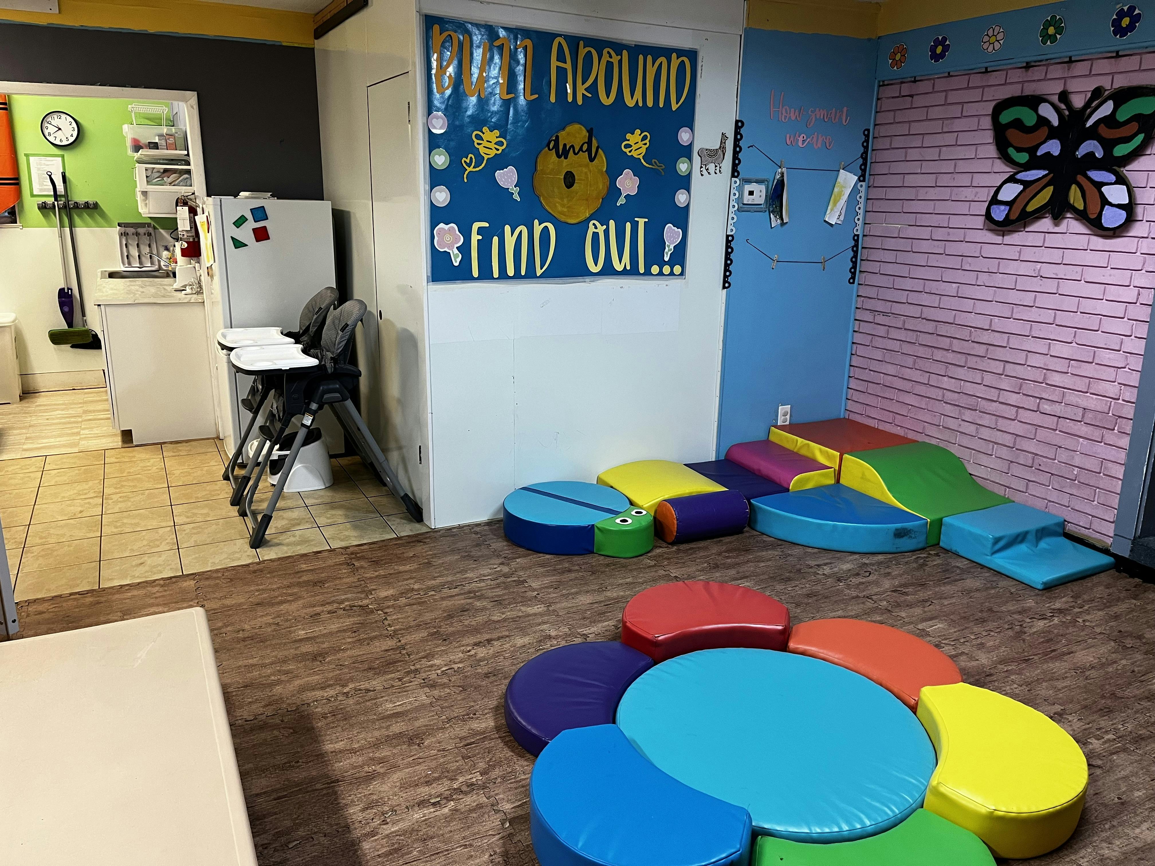 Playroom with soft play equipment and a kitchen area in the background
