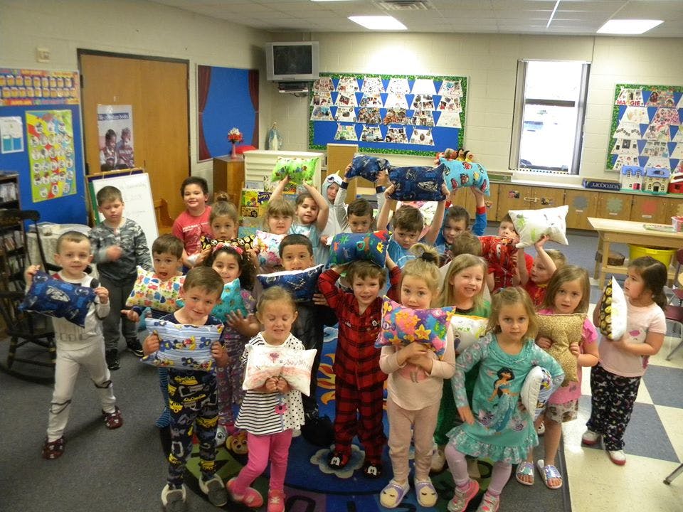 Group of children in pajamas holding pillows in a classroom