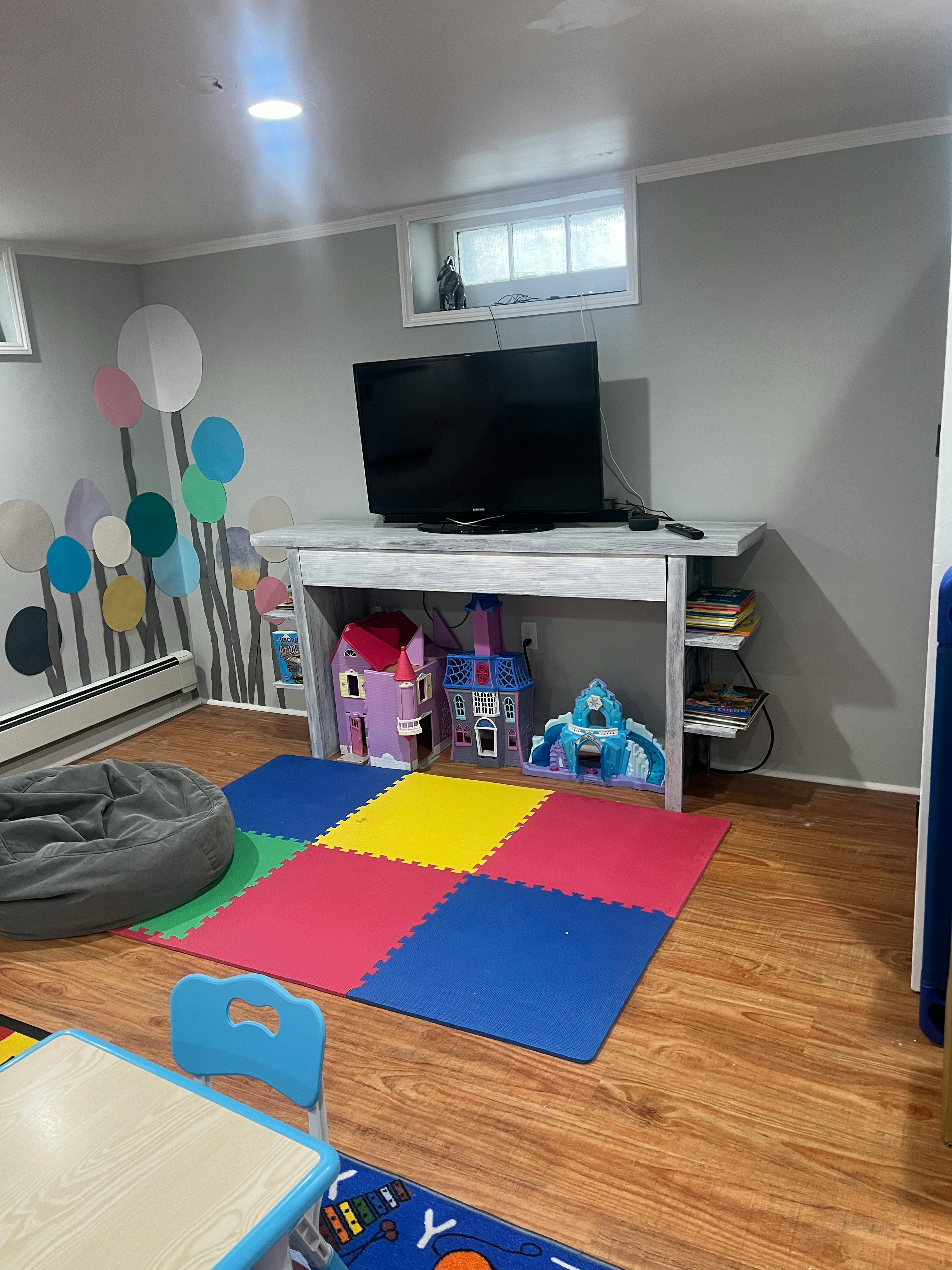 Playroom with TV, colorful floor mats, and toys