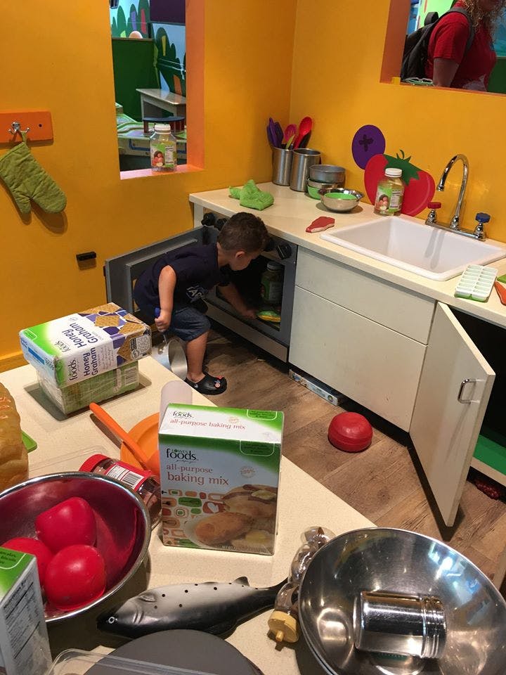 Child looking into an open oven in a play kitchen