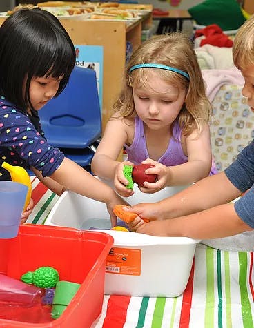 Children playing with toys in a water bin in a classroom