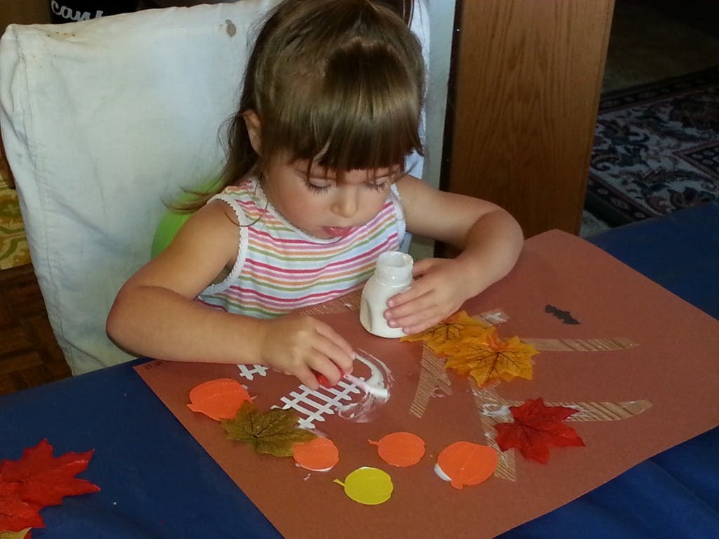 Child doing a craft with glue and paper cutouts