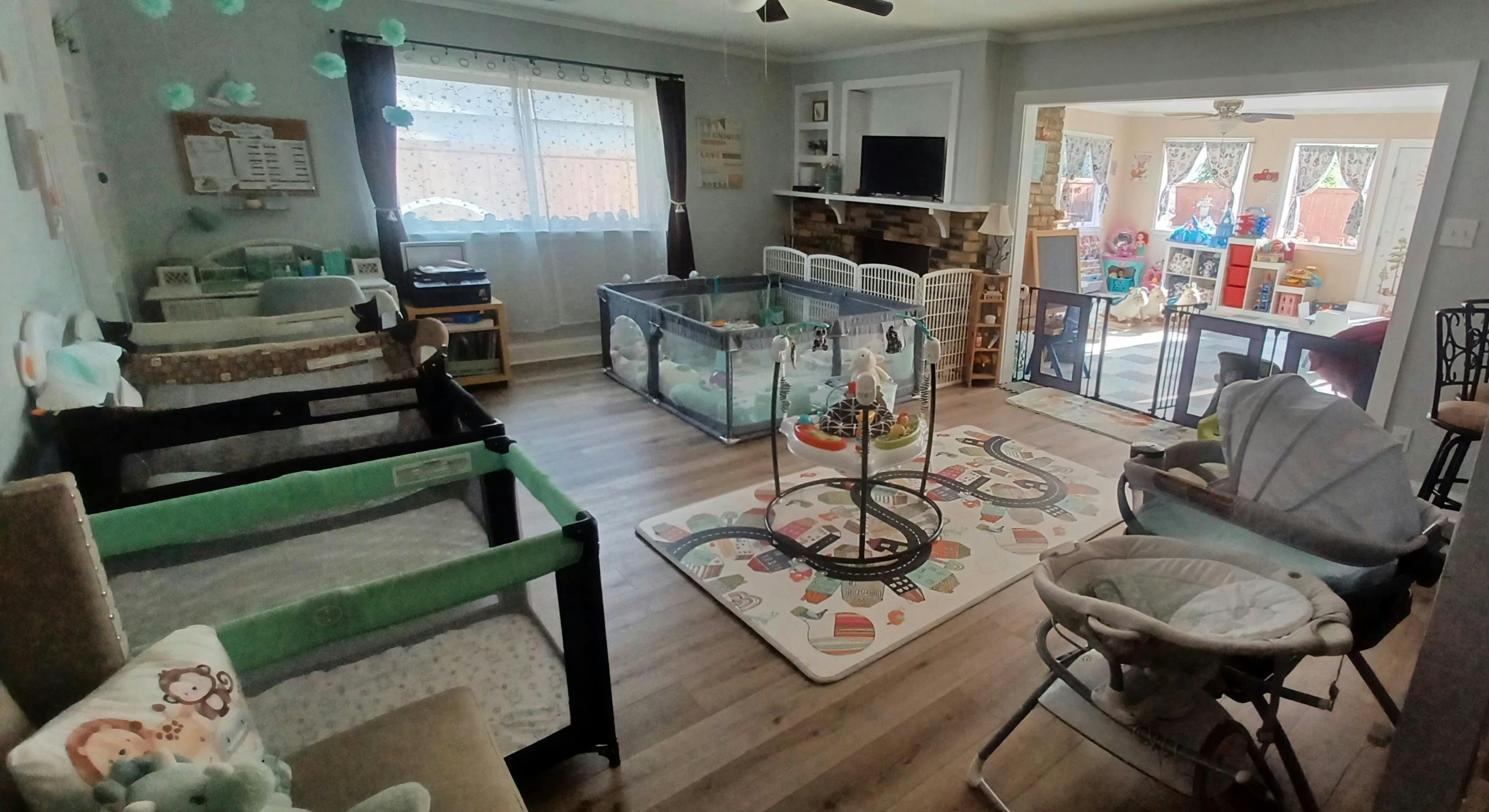 Living room set up with multiple playpens and a baby jumper