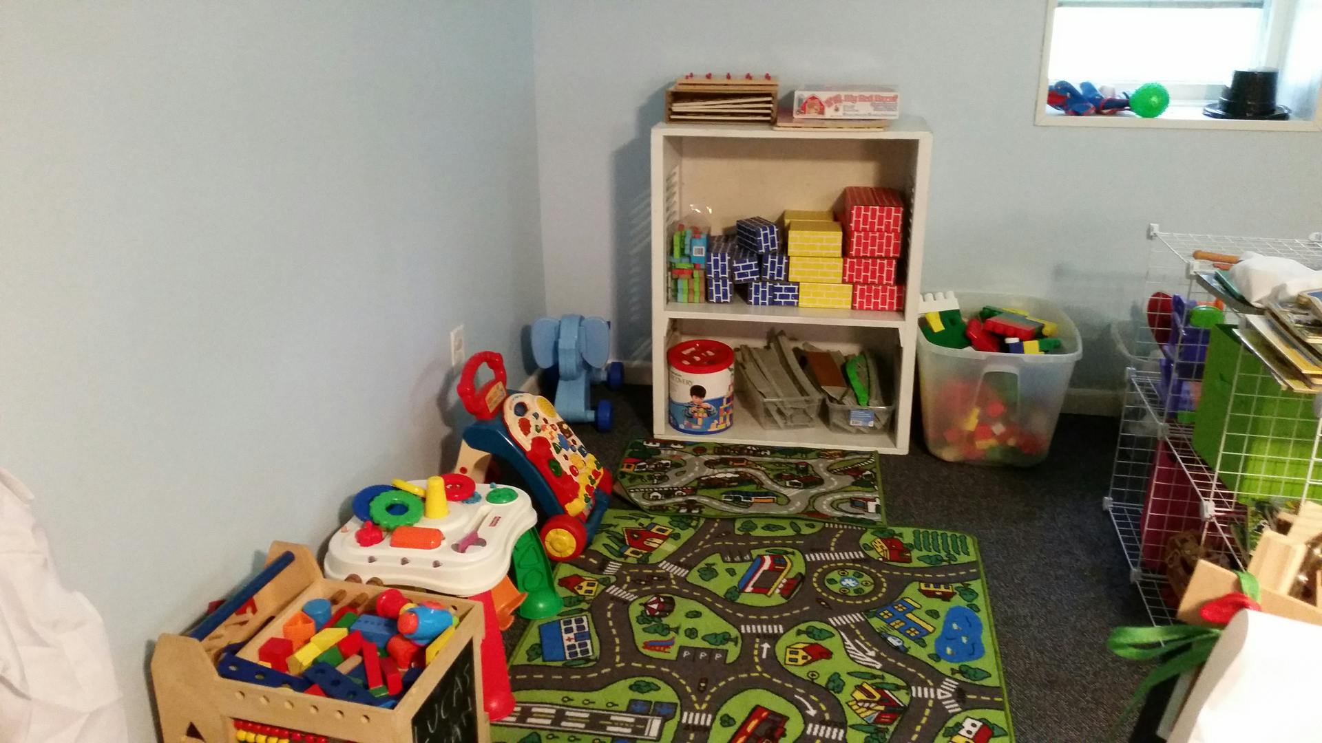 Playroom with toys, a road map rug, and storage shelves