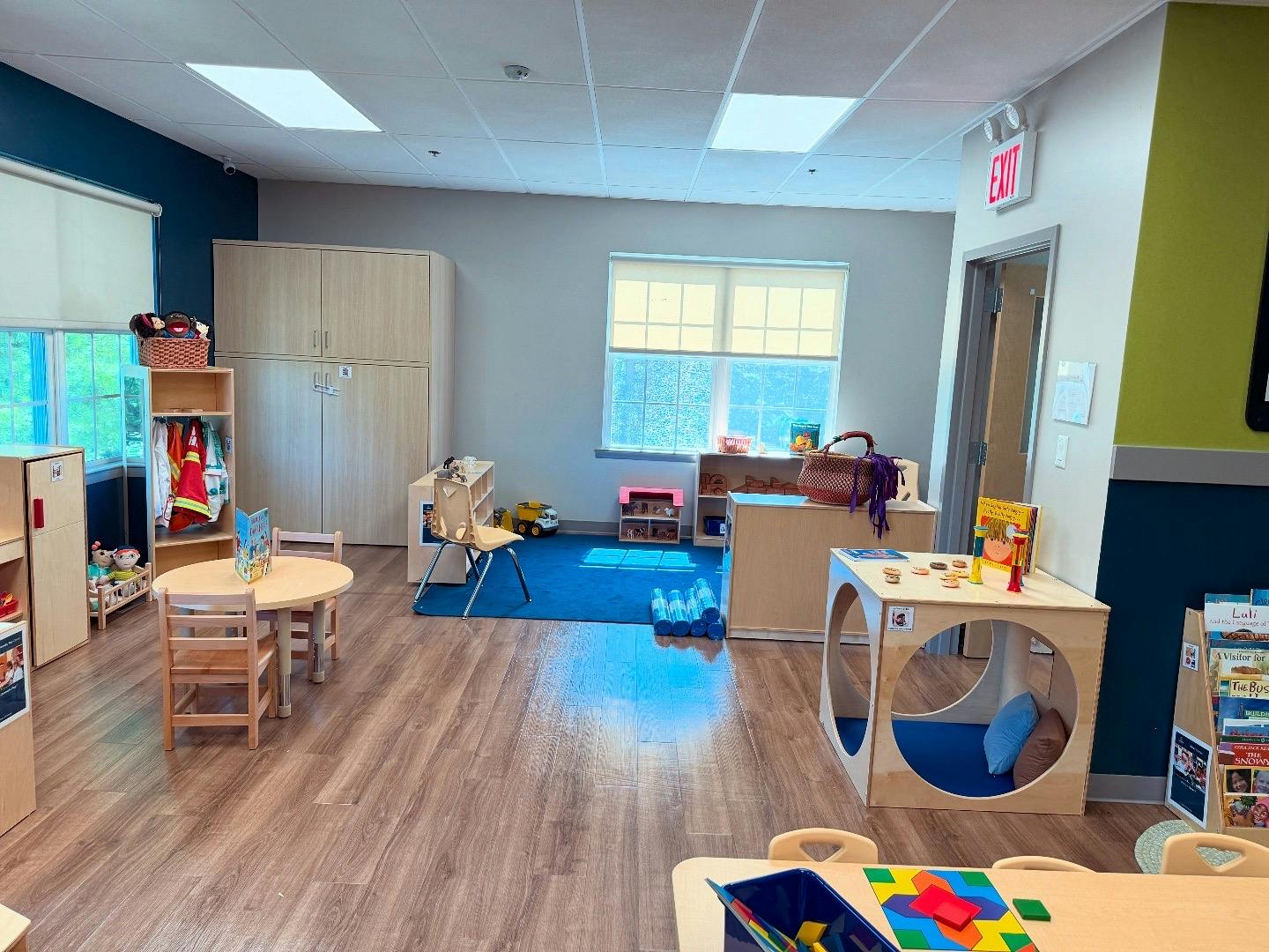 Empty classroom with small tables, chairs, and play furniture