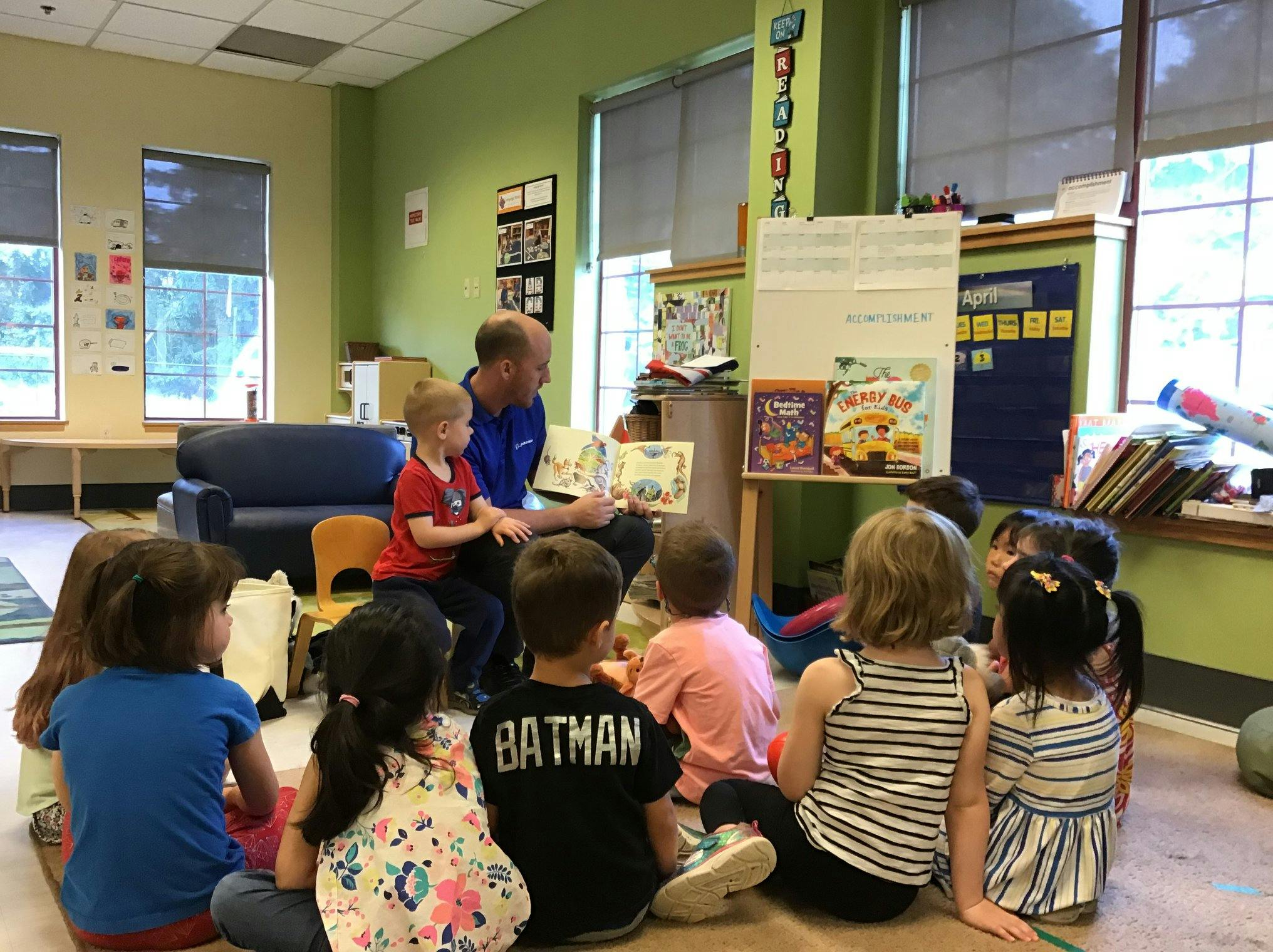 Adult reading a book to a group of children in a classroom