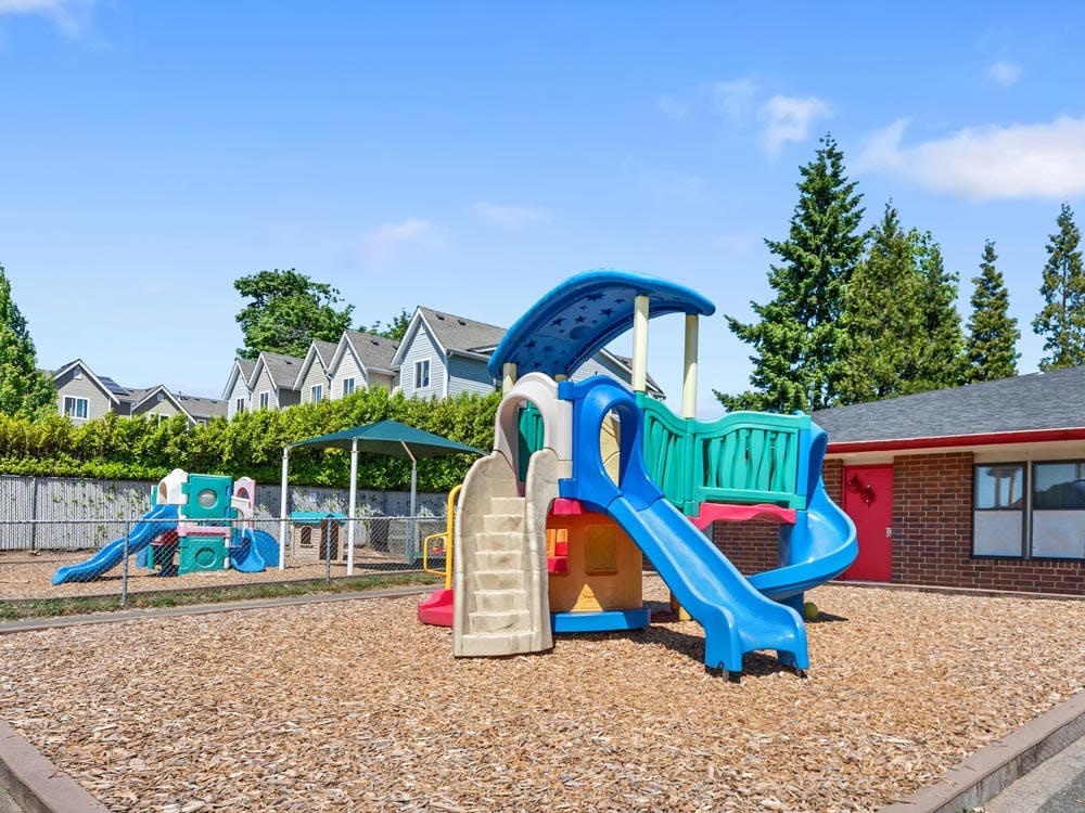 Empty outdoor playground with colorful plastic slides and climbing structures