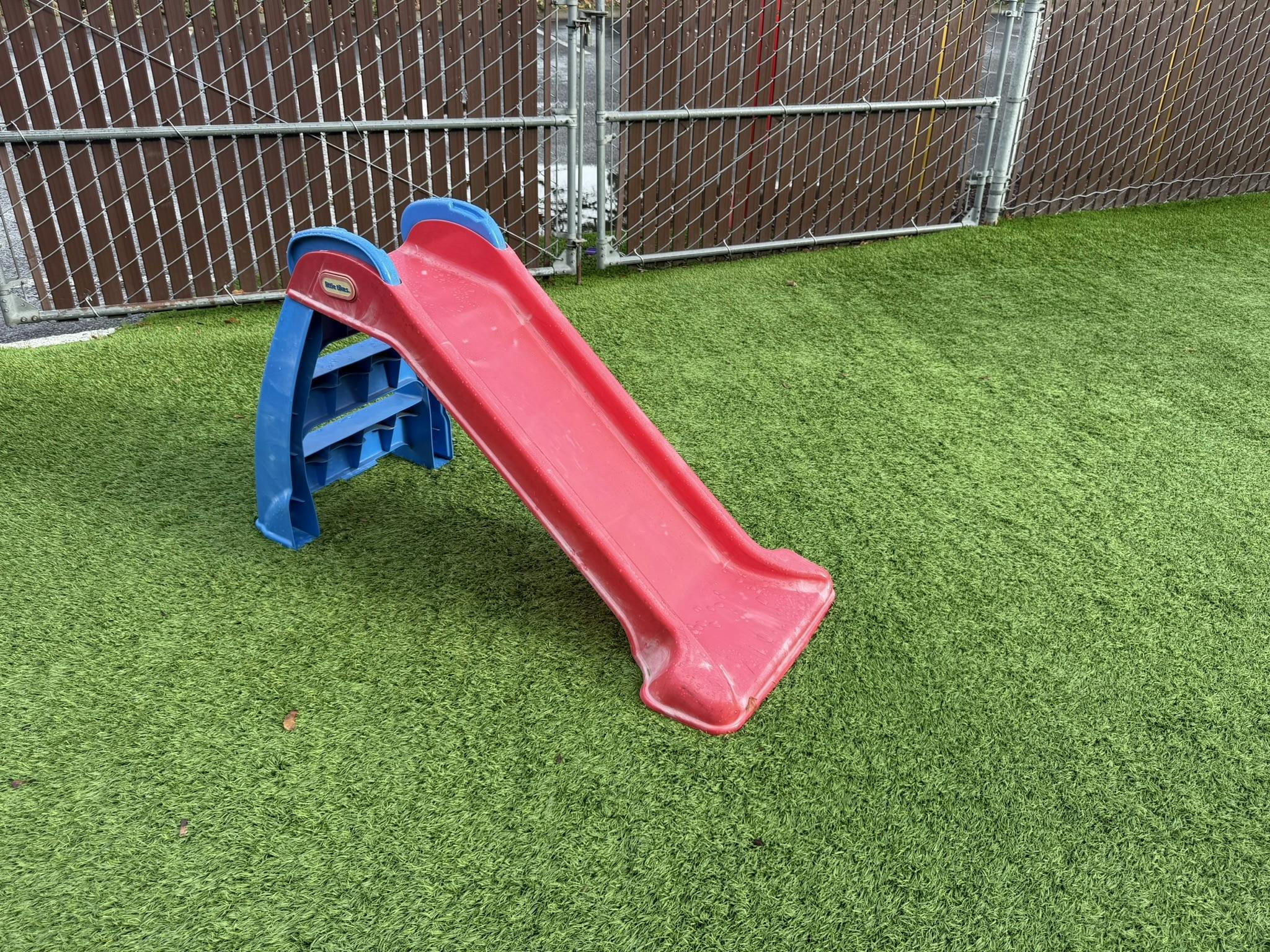 Red and blue plastic slide on green artificial turf
