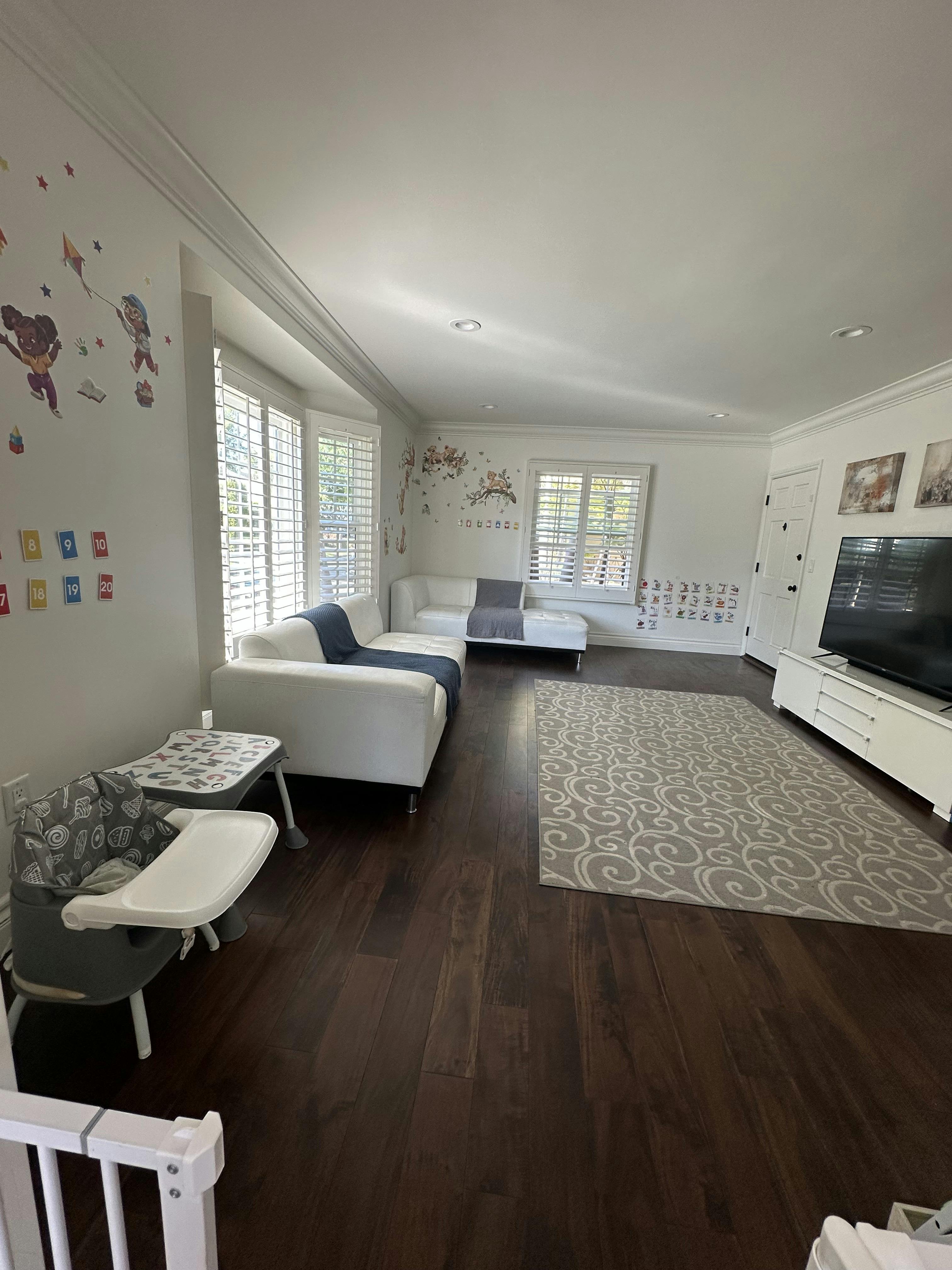 Living room with white sofas, a child high chair, and wall decorations