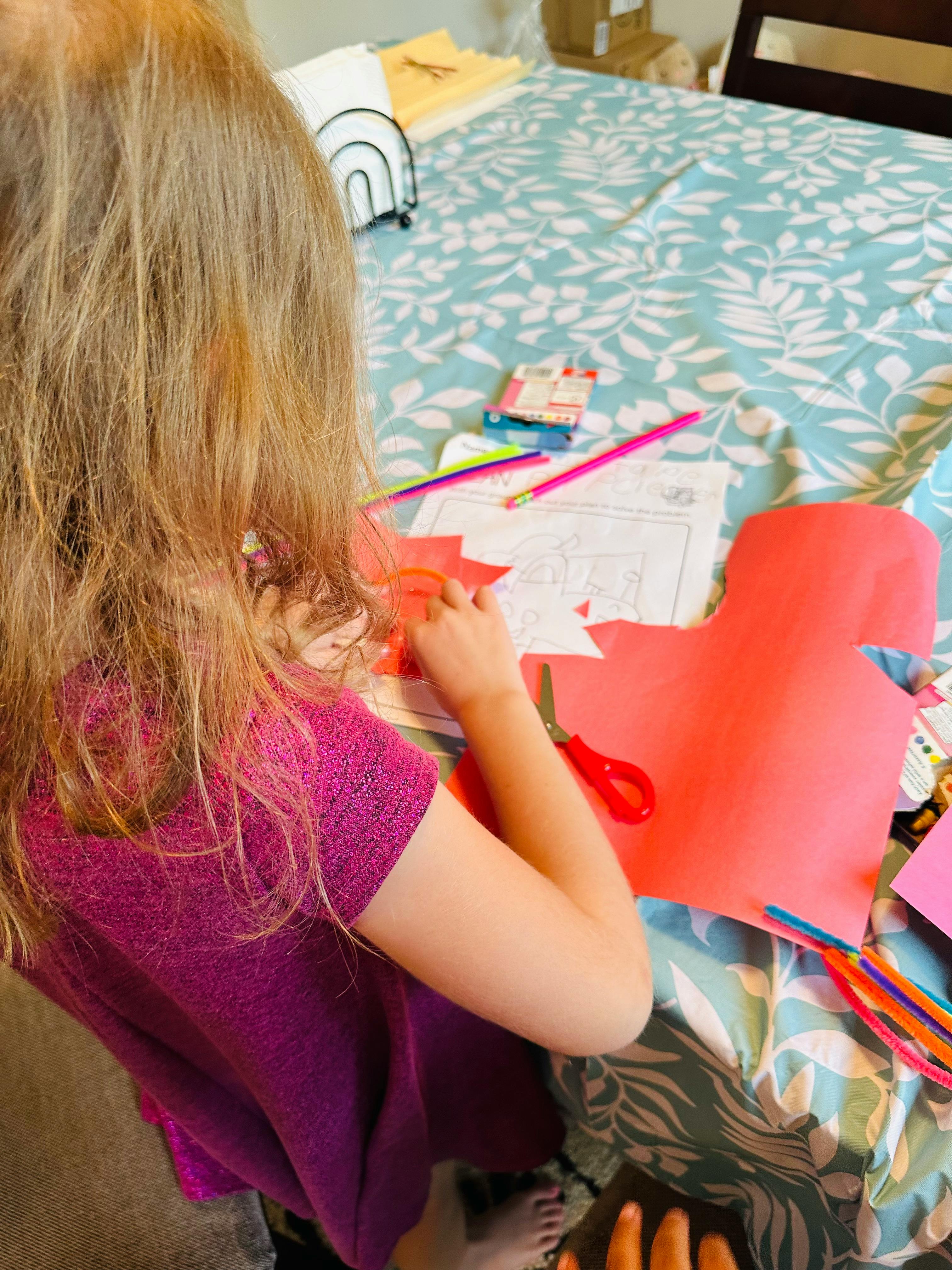 Child cutting red paper with scissors