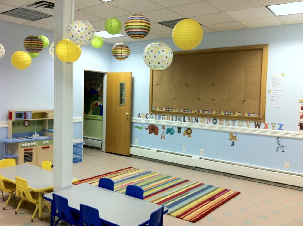 Classroom with tables, chairs, play kitchen, and hanging lanterns