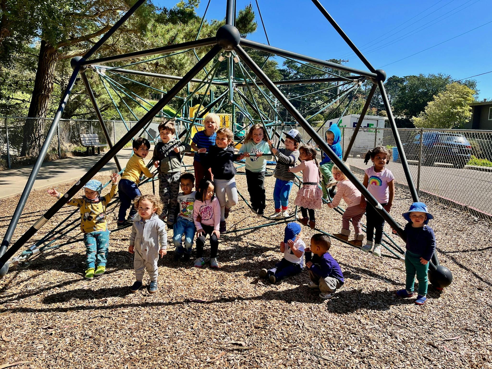 Group of children and adults on a playground climbing structure