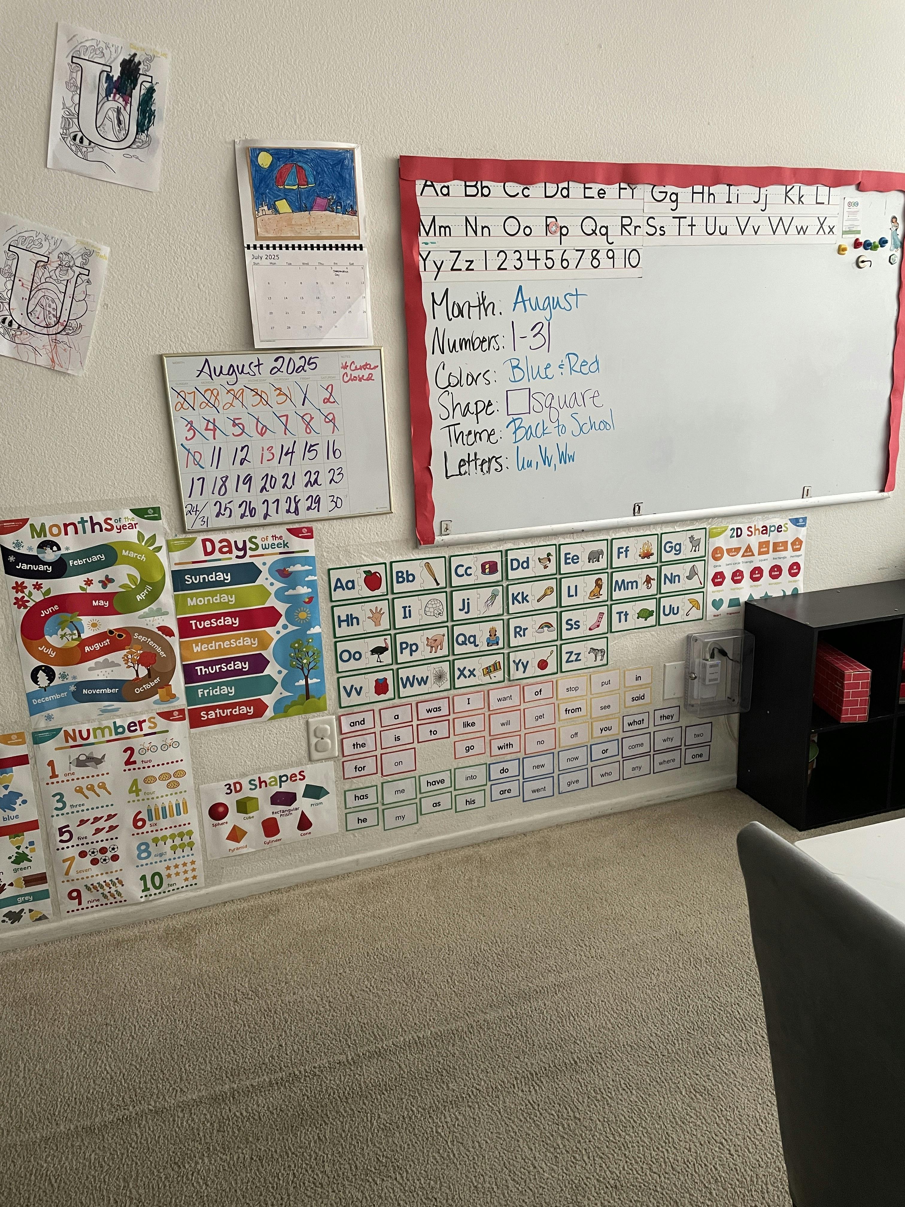 Whiteboard with alphabet and numbers, calendar, and learning charts on a wall