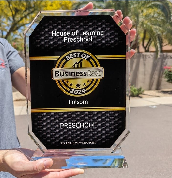 Person holding a "Best of BusinessRate 2024 Preschool" award