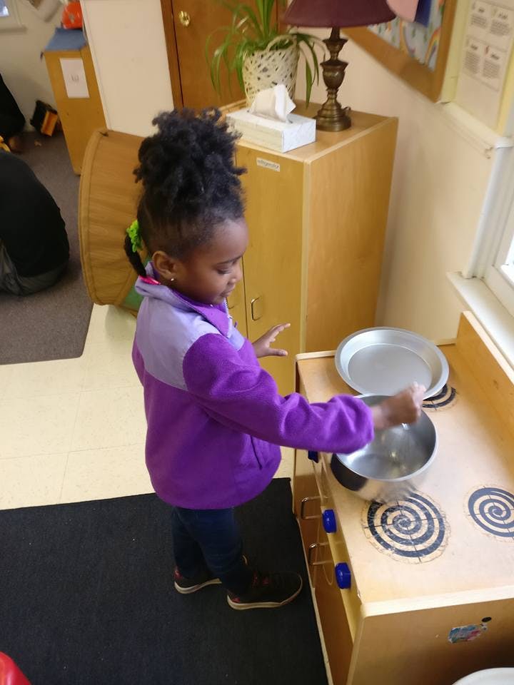 Child playing with a toy stove and pot