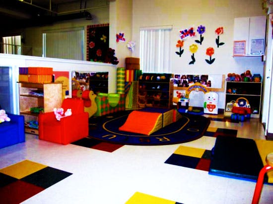 Playroom with colorful mats, soft play equipment, and shelves of toys