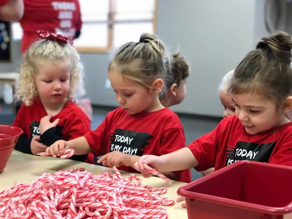 Children in red shirts sorting candy canes