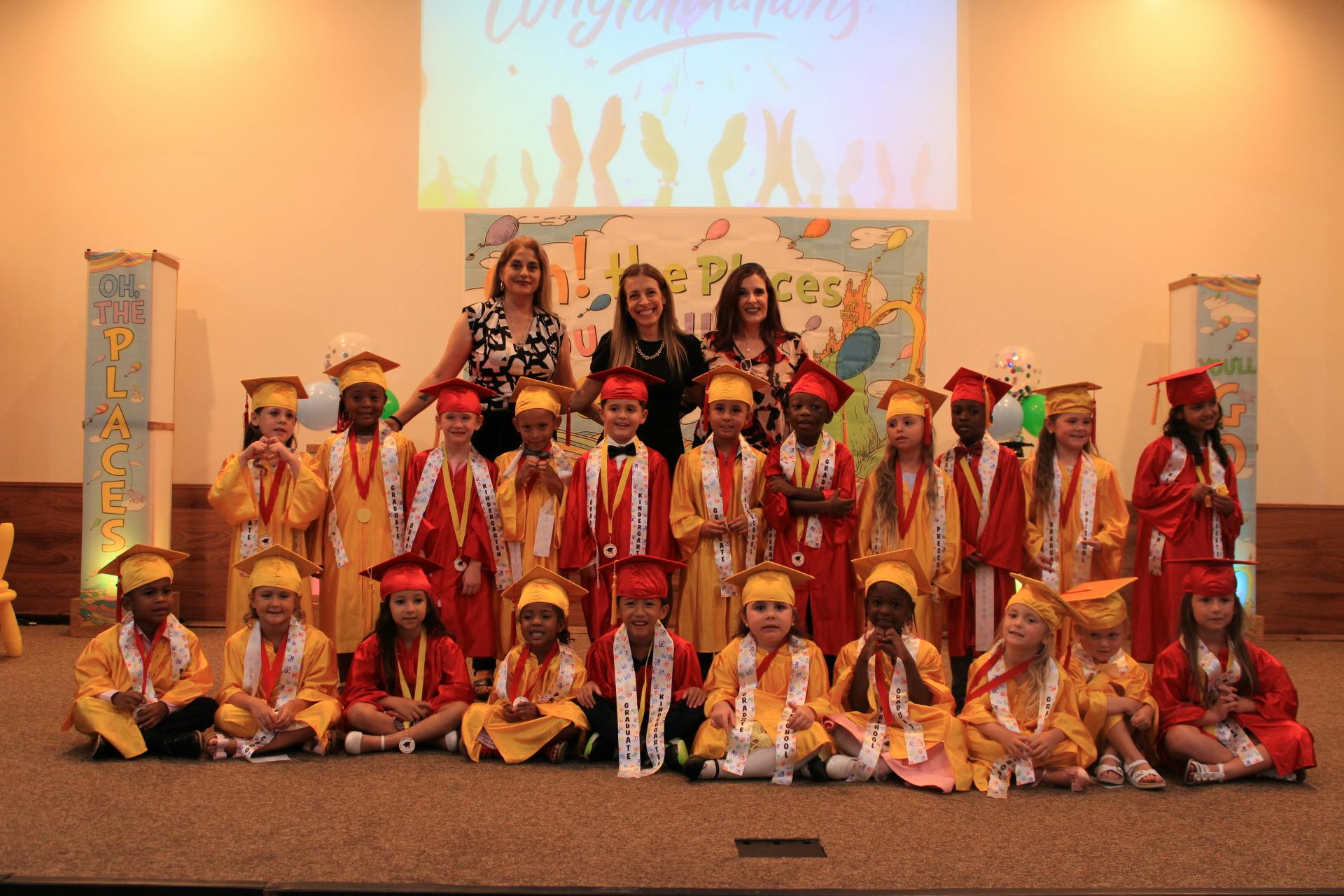 Adults and children in graduation caps and gowns posing for a photo