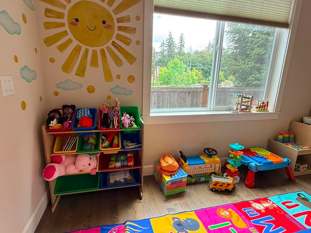 Playroom with a sun wall decal and shelves filled with children's toys
