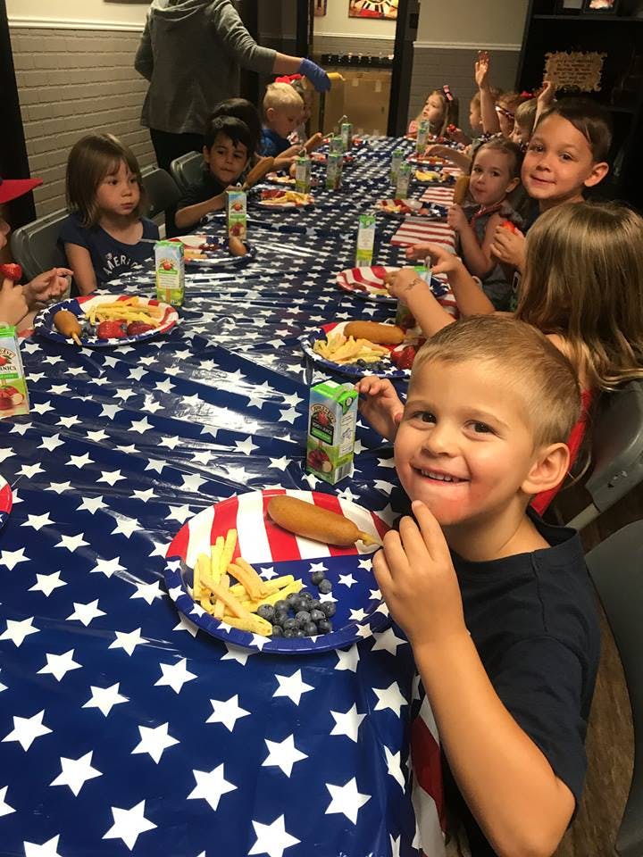Children sitting at a long table with a star-patterned tablecloth